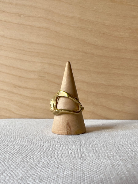 Brass hammered ring with a curvy stile and oval cutout in the middle.