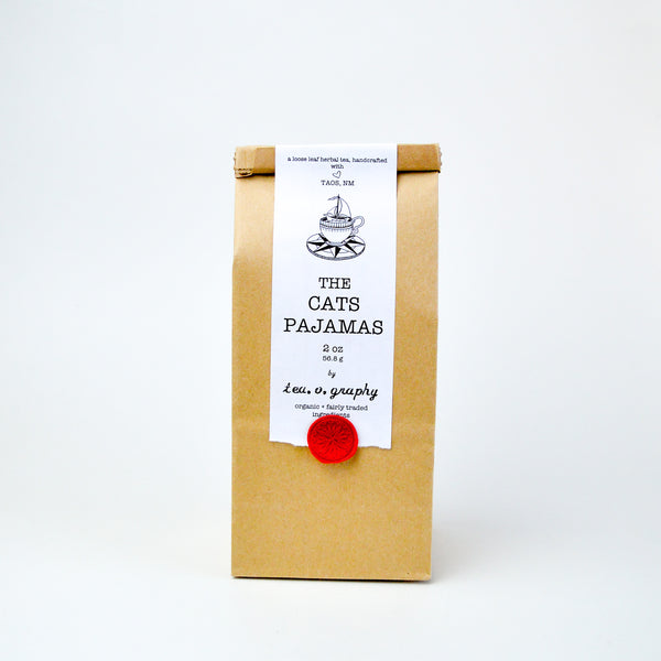 Brown paper Bag with a white label, held down by a red wax seal. the white label has black text reading "The Cat's Pajamas"