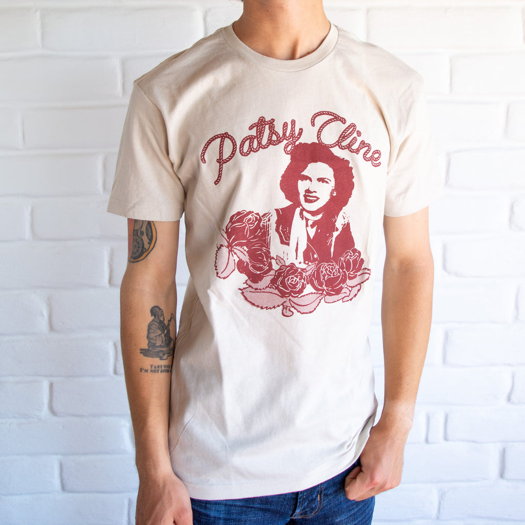 White shirt with patsy cline printed in red, roses under her and red rope spelling out "Patsy Cline" above her.