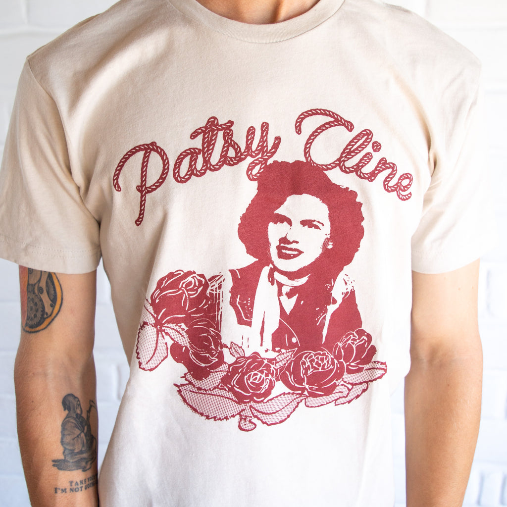  White shirt with patsy cline printed in red, roses under her and red rope spelling out "Patsy Cline" above her.