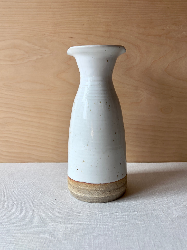 White speckled ceramic carafe with a beige bottom. the carafe has a wide mouth