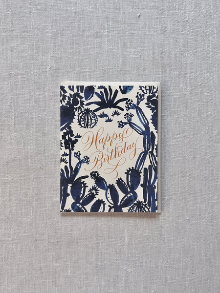 white card with various blue succulents and "happy birthday" written in gold at the center