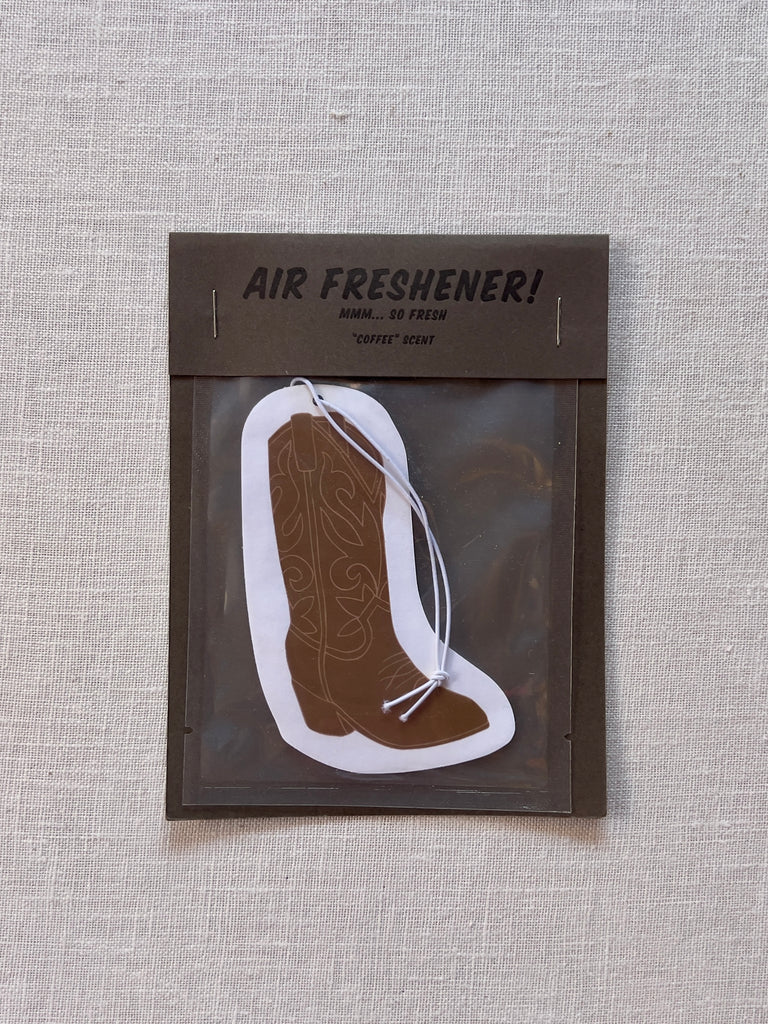 Air freshener shaped like a cowboy boot. the boot is brown with a white boarder and string.