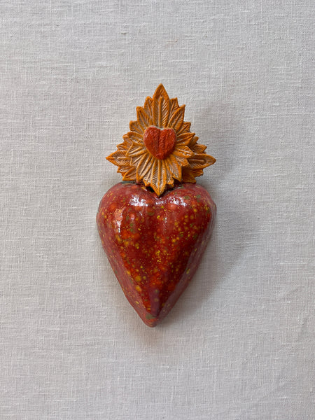 Red Milagro heart with a yellow sunburst at the top