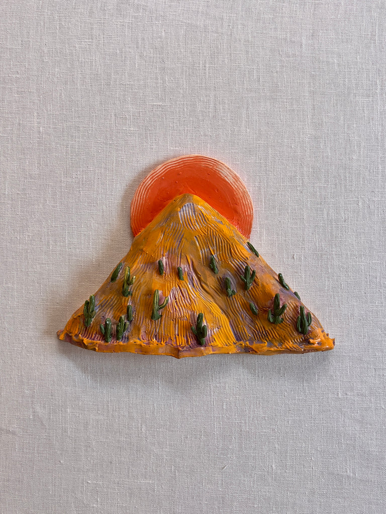 Ceramic yellow mountain with an orange sun at the top and green cactus about it
