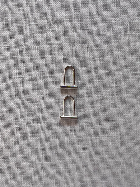 Small sterling silver earrings in the shape of a bile lock.
