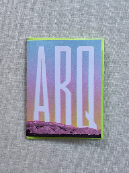 Card showcasing the sandia mountains at sunset and bold lettering over it reading "ABQ"