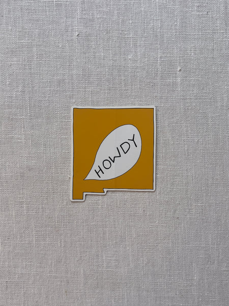 White sticker with a yellow shape of new mexico and a text bubble with yellow text reading "howdy"