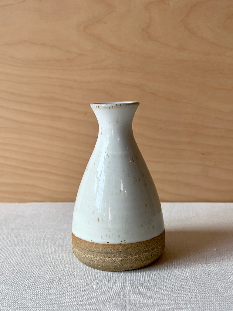 White speckled teardrop shaped vase with a brown ring at the bottom
