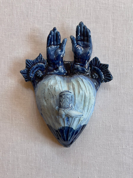 Blue heart with hands coming out of the top and a boot with spurs in the middle