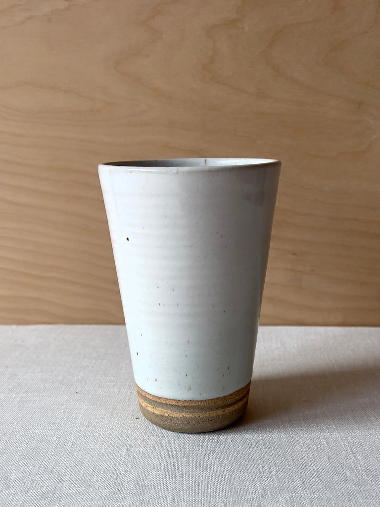White speckled ceramic tumbler with a brown ring at the bottom.