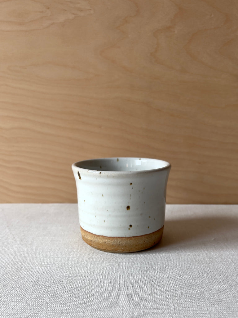 Small white ceramic speckled planter with a brown ring at the bottom.