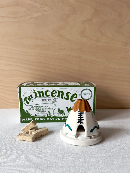 Small white and brown ceramic teepee with brick incense sitting next to it.