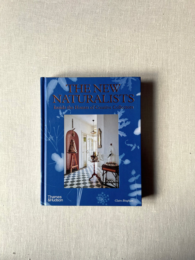 Blue cover of the book " The New Naturalists" in the middle is a photo of a thoughtfully decorated space