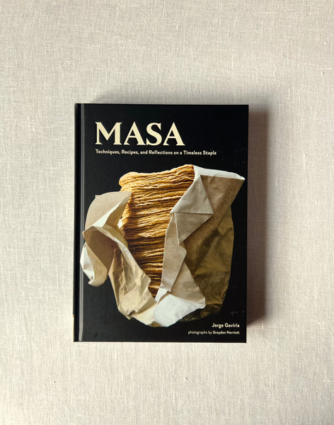Black cover of the book "Masa: Tecniques, Recipes, and Reflections on a Timeless Staple"  by Jorge Gaviria. a stack of corn tortillas are on the cover.