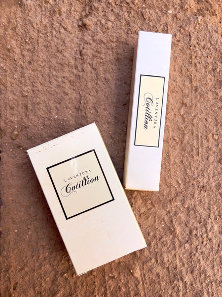 Two White rectangular paper perfume boxes, one wider than the other, with a white label and black text that reads "l'aventura cotillion."