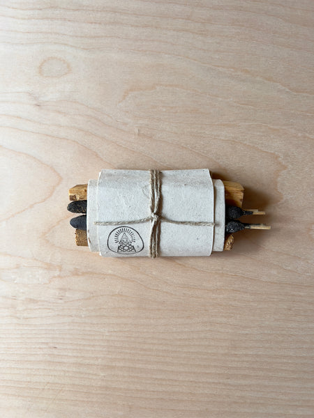 white paper and twine packaging holding together a bar of soap, palo santo and copal incense.