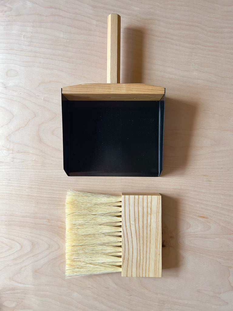 Dark wood hand broom and dustpan with black metal sides and blonde horse hair bristles.