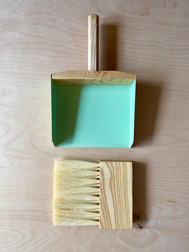 Dark wood hand broom and dustpan with green metal sides and blonde horse hair bristles.