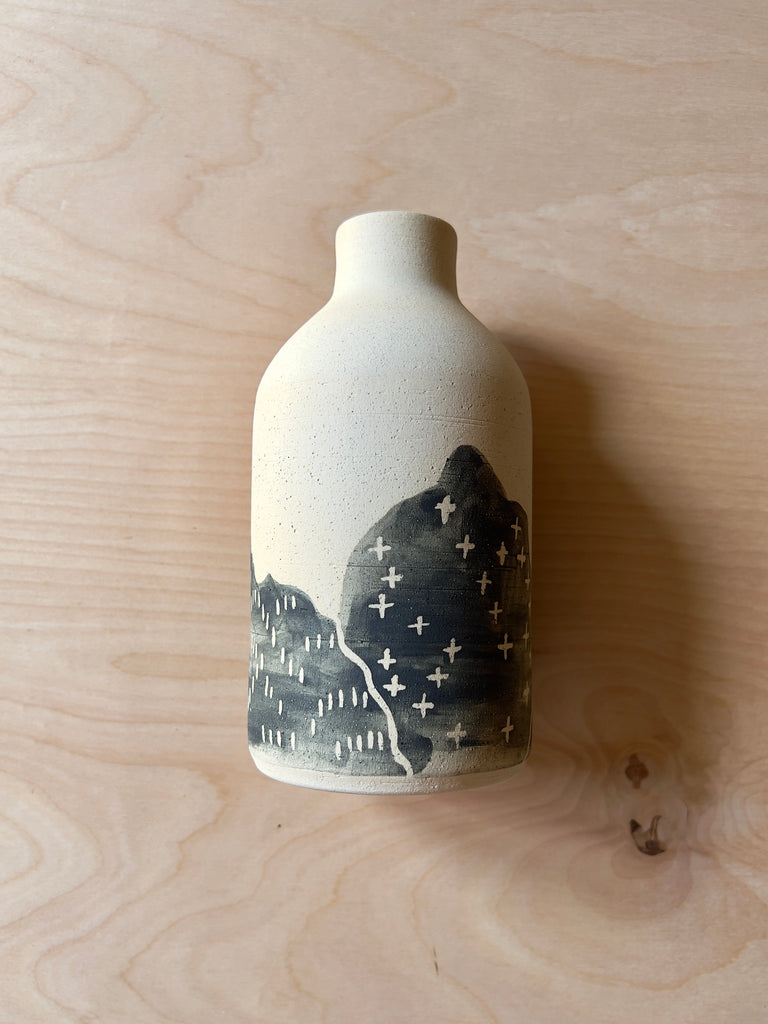 White and black ceramic vase depicting black and white mountains at the bottom.