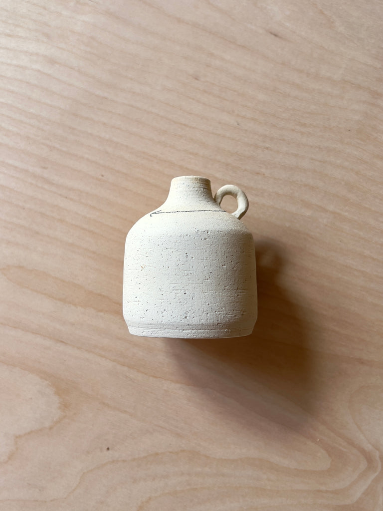 mini white ceramic jug with  a black arrow rounding the top