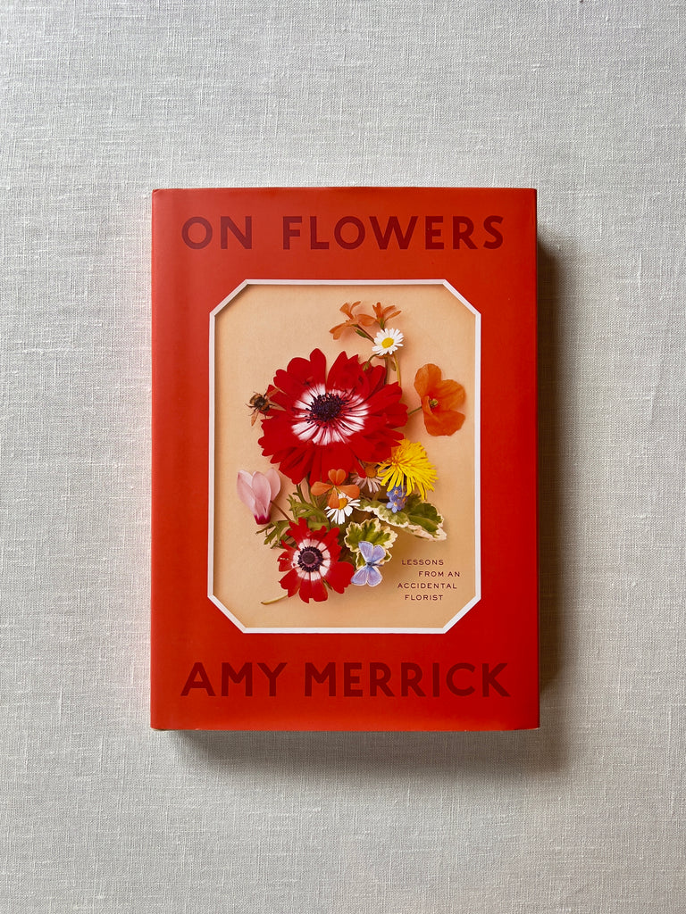 Red cover of the book "On Flowers" By Amy Merrick. the middle of the cover has flowers of varying covers