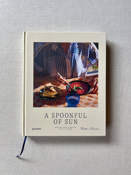 White cover of the book "A Spoonful Of Sun" with someone outside eating food