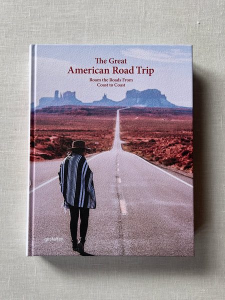 Cover of the book "The Great American Road Trip." There is a person standing on a road staring out at the vast desert mountain scene.