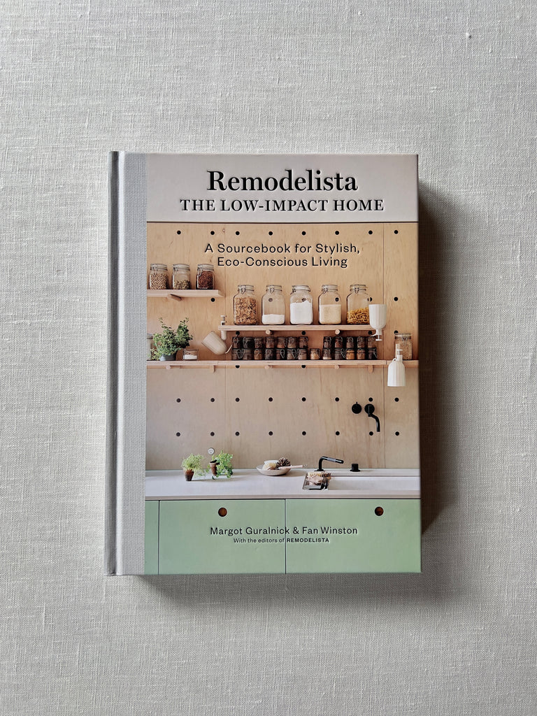 Cover of the book "Remodelista: The Low Impact Home" By Margot Guralnick. The cover shows jars full of shelf stable goods sitting on shelves above a counter and sink.