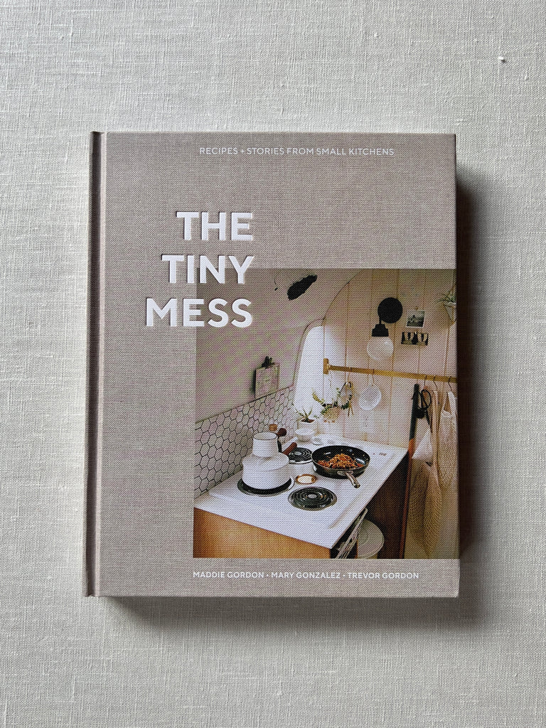 Grey cover of the book "The Tiny Mess" By Maddie Gordon.  A small kitchen with pots cooking food are shown in the middle.