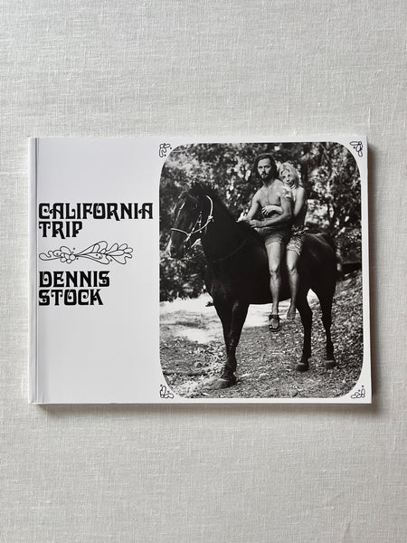 A cover of the book "California Trip" by Dennis Stock. The cover is white with a black and white photograph of a man and a woman sitting on a horse together. 