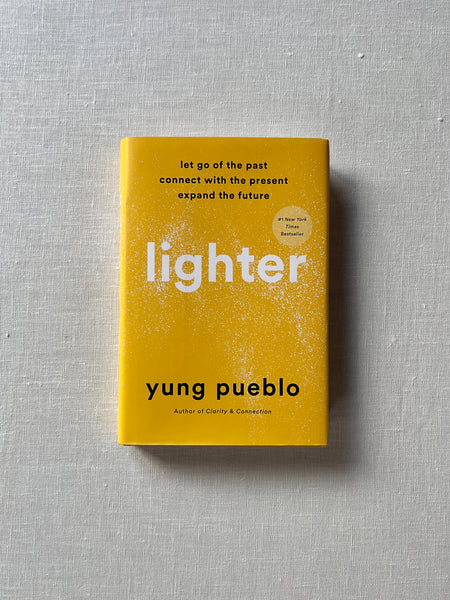 Bright yellow cover of the book "Lighter" by Yung Pueblo. beyond the text stating the name of the book and author, there's black text at the top reading "Let go of the past, connect with the present, expand the future."