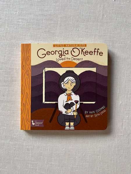Cover of the book "Little Naturalists: Georgia O'Keeffe Loved the Desert" by Kate Coombs. the cover shows artwork of Georgia O'Keeffe in front of a purple gradient canvas.