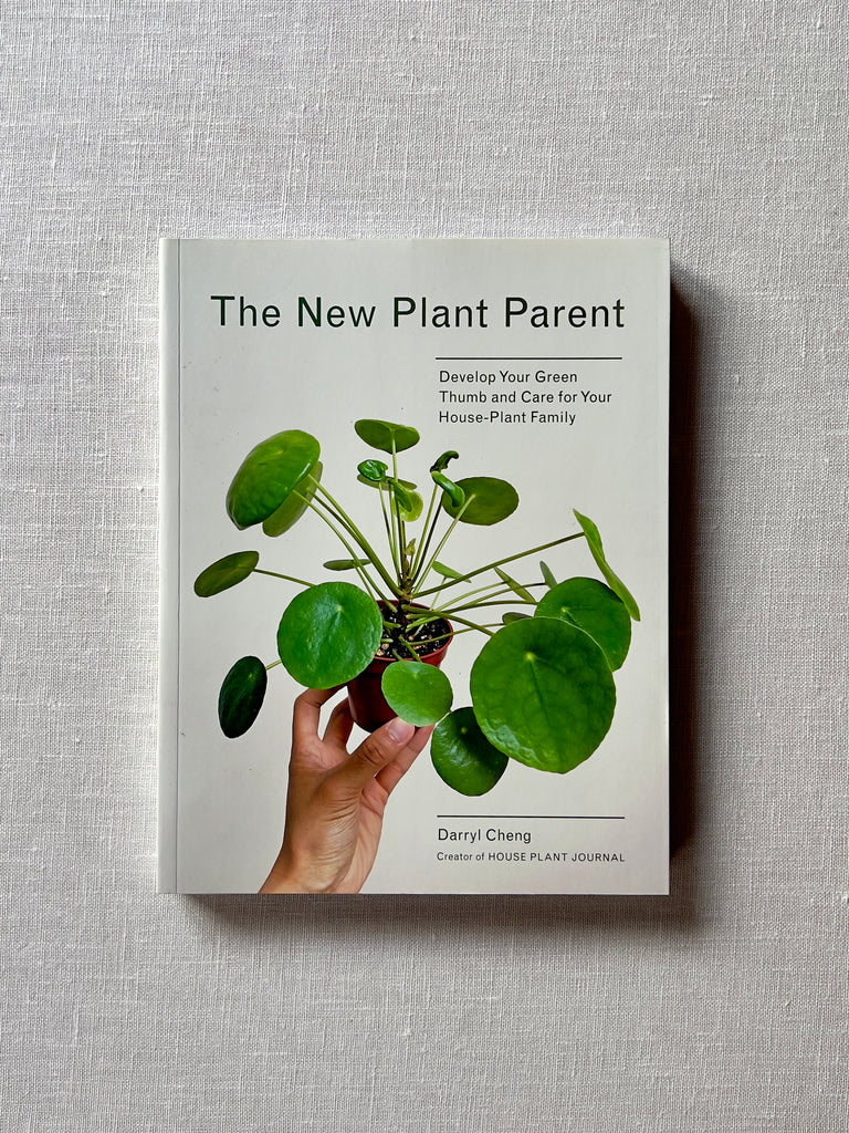 A cover of the book "The New Plant Parent" by Darryl Cheng. The cover is a photo of a hand holding a potted plant. Text reads "Develop Your Green Thumb and Care for Your House Plant Family."