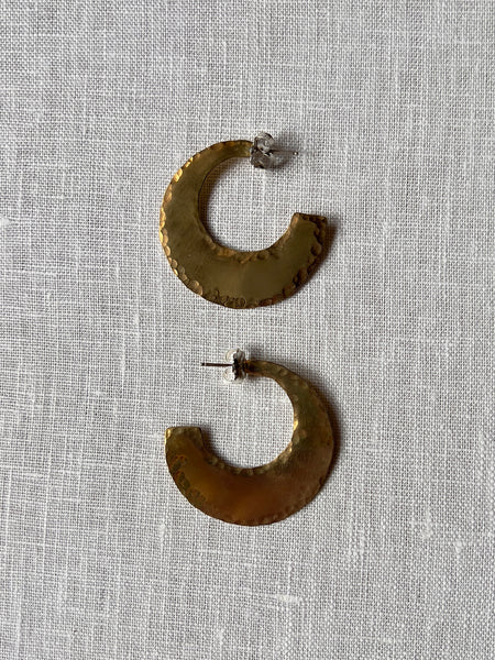 Pair of golden hammered earrings in the shape of an exaggerated crescent moon.