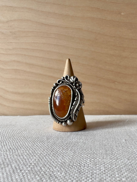 Oval shaped sterling ring with a brown stone and flowers and feathers in sterling silver around the stone