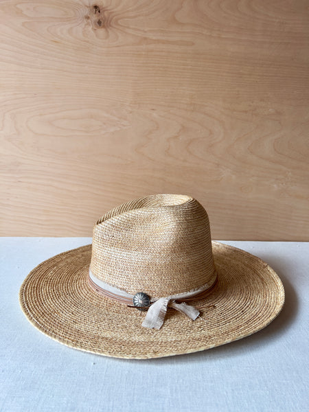 Hand woven flat brim hat with a leather and linen hat tie and a large stylized metal bead