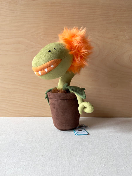 Stuffed potted plant with a toothy smile and fluffy orange hair