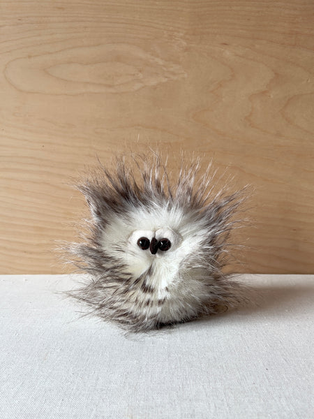 Small, round stuffed owl with messy hair all around