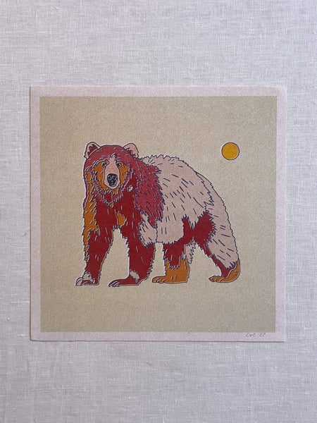 Art print of a grizzly bear on a green/beige background. The bear's fur is different colors of red, orange, and tan. there is a small sun overlooking the bear in the rightmost corner