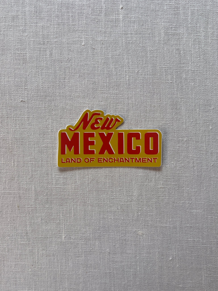 Yellow sticker with red text reading "New Mexico, Land of Enchantment"