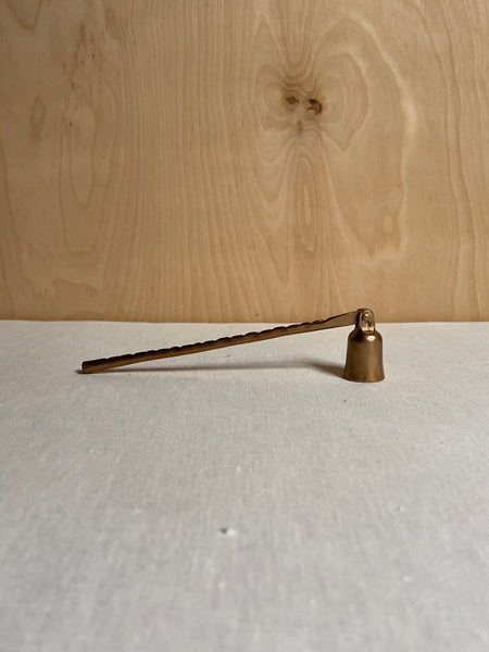 Brass candle snuffer shaped like a bell with a long candle