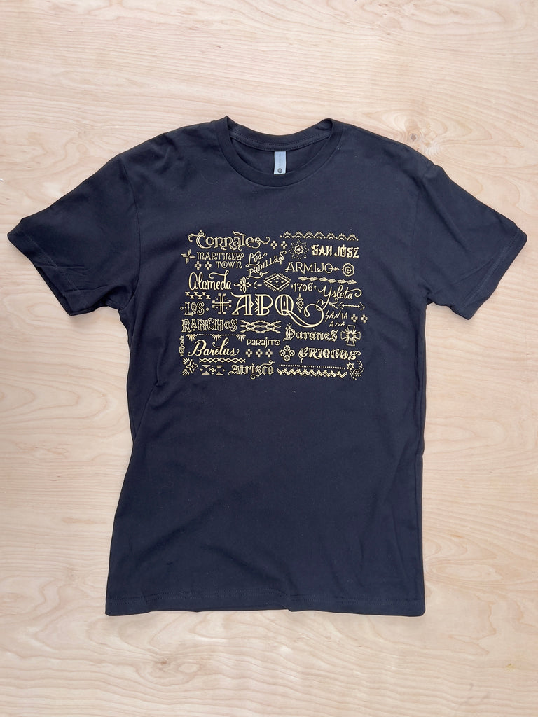 Black T-shirt with new mexico cities and towns in gold lettering and various fonts