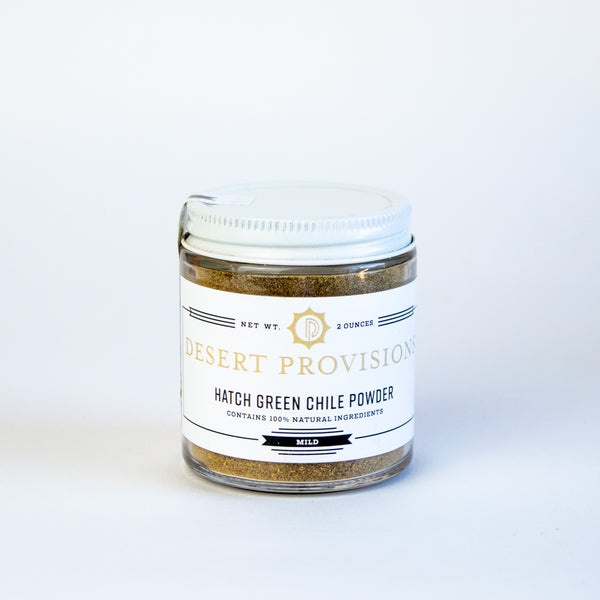 Glass container with a white top and white label. the label has gold and black text reading "desert provisions hatch green chile powder. contains 100% natural ingredients."