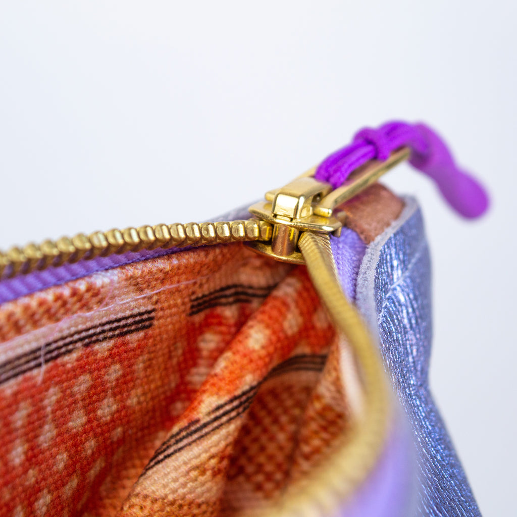 Medium metallic purple pouch. showcasing its gold zipper, purple zipper pull, and bronze leather zipper catch.