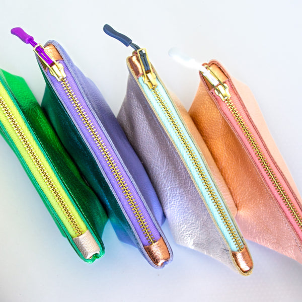 Four medium sized metallic pouches. From left to right: green, purple, silver, and pink.