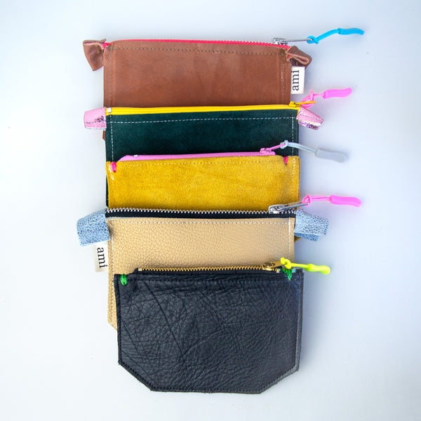 Five small leather pouches from bottom to top: Black, tan, yellow, green, and brown.