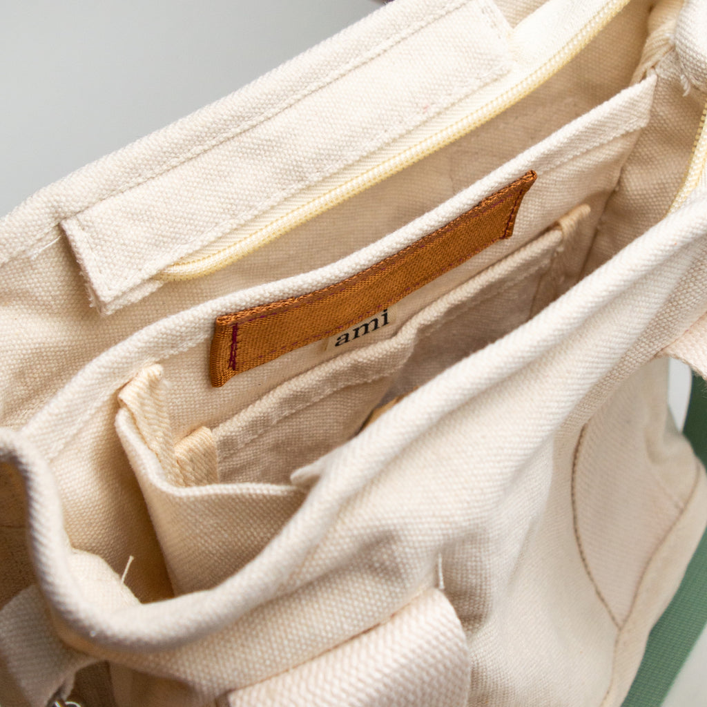 top down view of a white bag to showcase its four pocket compartments and beige tag reading "ami."