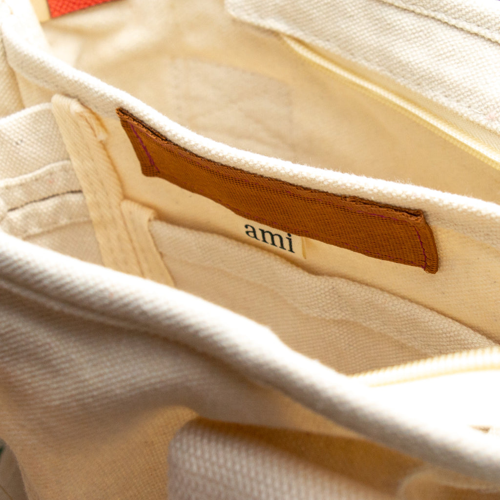 top down view of a white bag to showcase its four pocket compartments and beige tag reading "ami."
