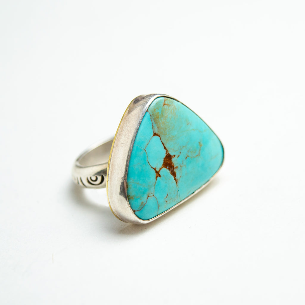 One large turquoise and silver ring sitting on a white backdrop.